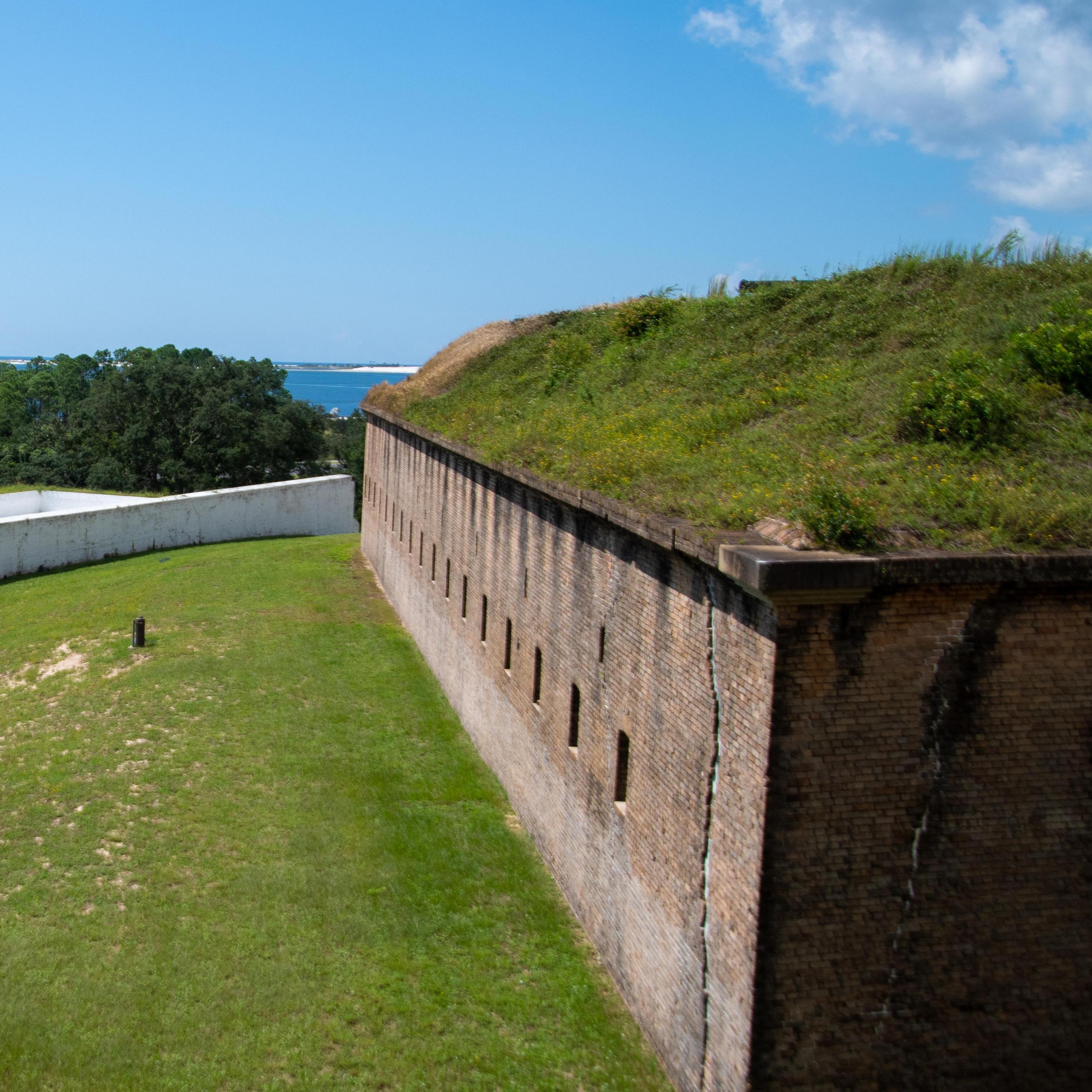 A brick fort overlooks sunny beaches and the sea.