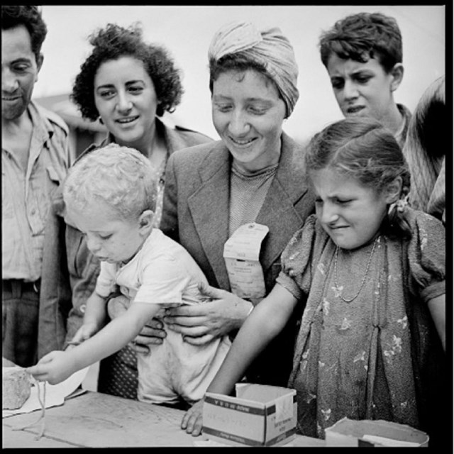 Women and children smiling in front of a table with papers on it