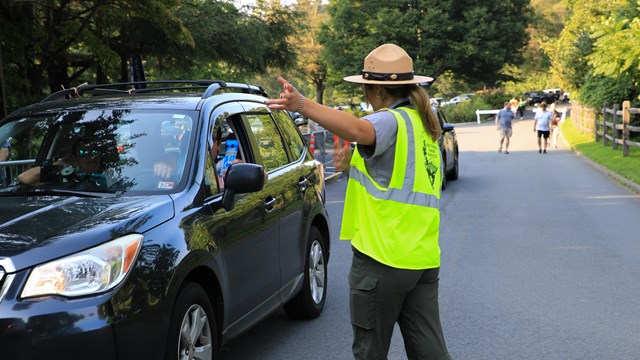 Female ranger giving directions to a car.