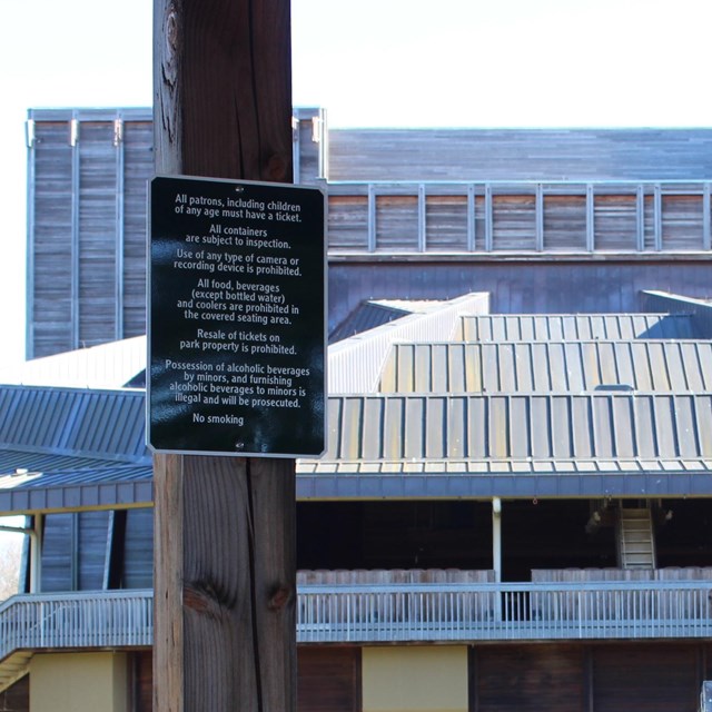 Green sign with House rules with Filene Center in the background