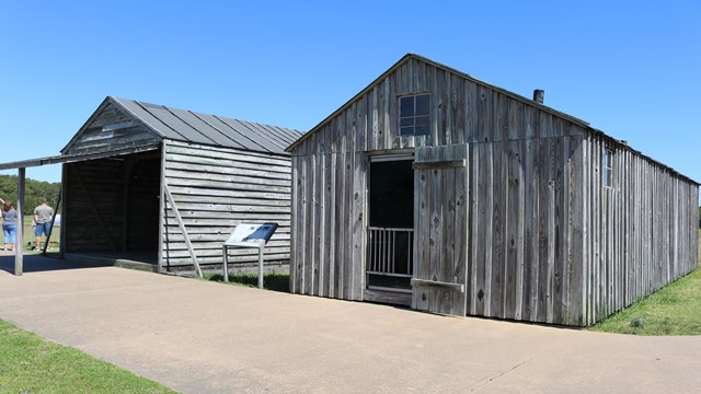 Two wooden replica buildings side by side with a sidewalk in front of each