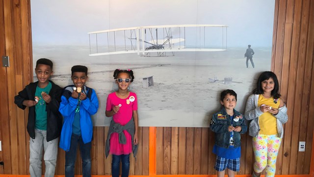 five children stand together against a wall showing their junior ranger badges proudly