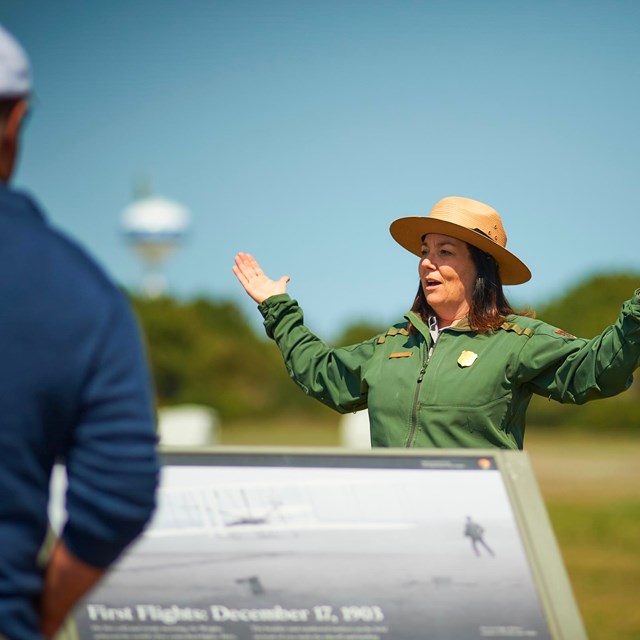 A park ranger gestures to park visitors.