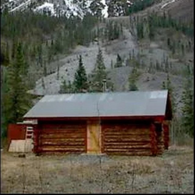 A picture of Peavine Cabin with mountains in the background.