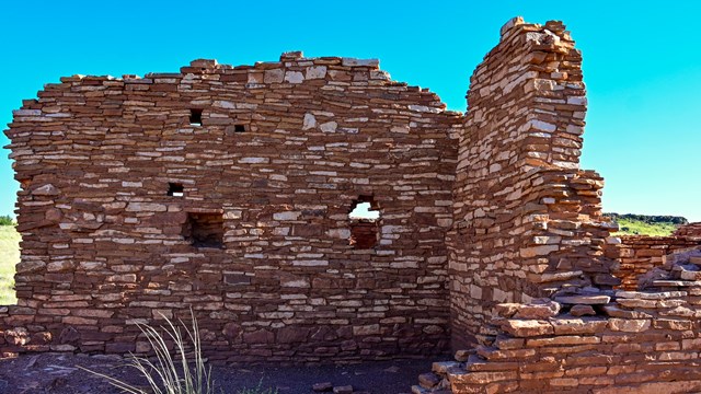 A red sandstone pueblo is set against a blue sky