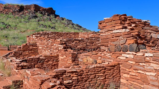 A small red sandstone pueblo sits below hilltop remains which include some black basalt.