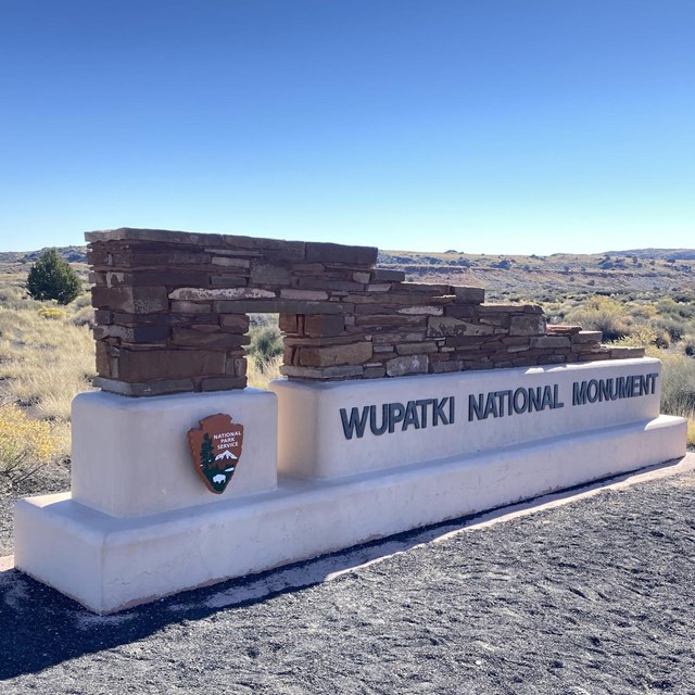 A stone and concrete sign announcing Wupatki National Monument