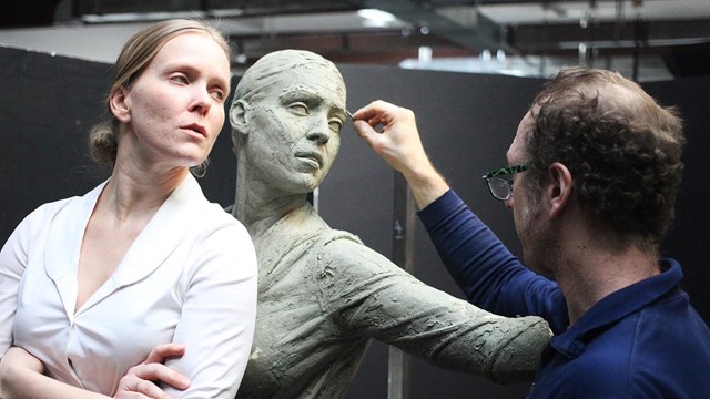 A sculptor shapes the clay model of one of the statues of A Soldier's Journey