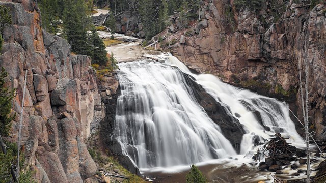 A waterfall cascades down a cliff, spreading out in a triangular shape.