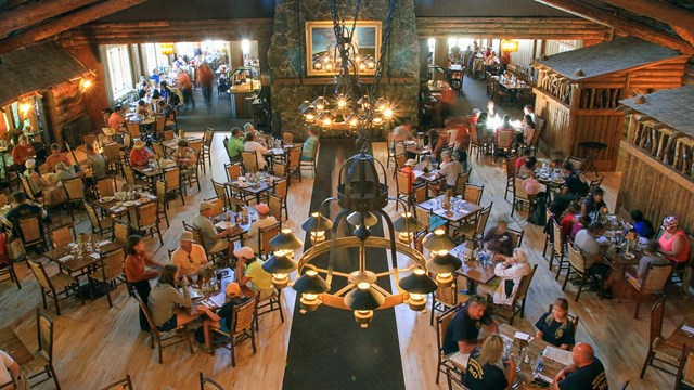 People sitting around tables in a large dining hall and eating.