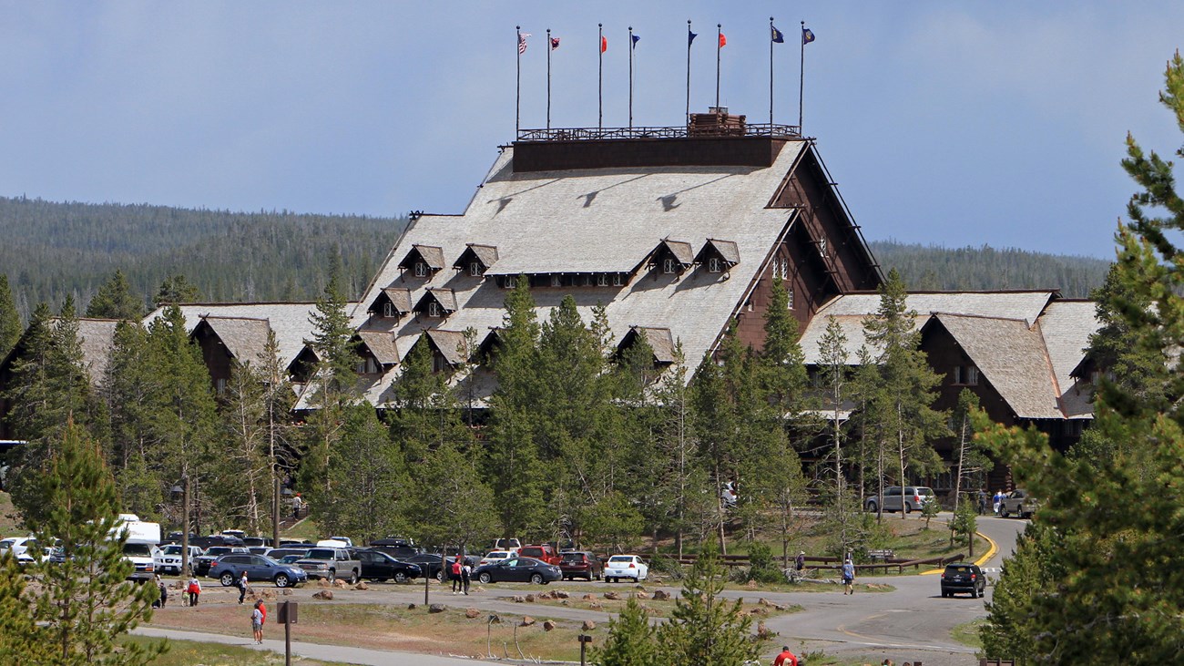 A large, A-frame-style log lodge rises above surrounding conifer trees.