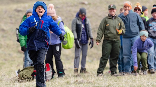 A students runs in front of classmates as part of an outdoor activity.