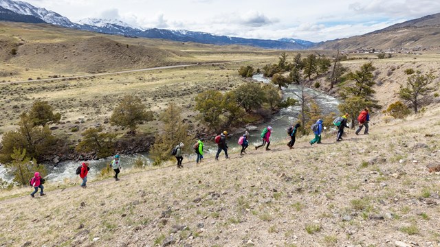 Students hike along a trail near a river.