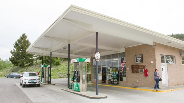 A brick building with gas pumps beneath an overhanging roof.
