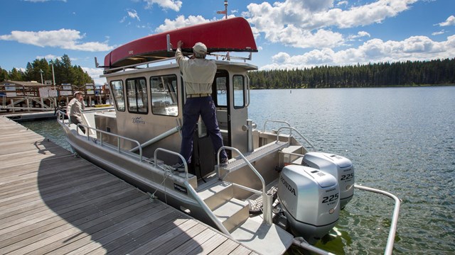 A person stands on a boat and loads up a canoe shuttle.