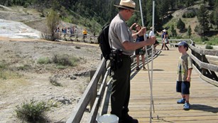 A young visitor learns about hot springs from a ranger.