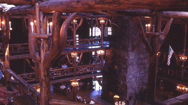 Gnarled wooden posts hold up the second floor balcony with the stone fireplace visible below.