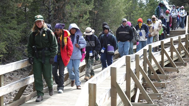 A ranger leads a group of schoolchildren down a long boardwalk.