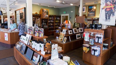 Books, water bottles, and bear spray are displayed on shelves within a store.