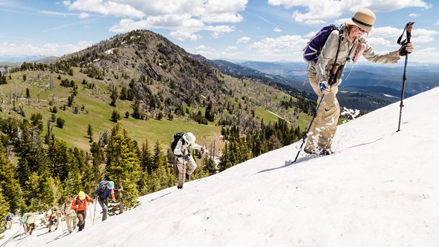 A hiker walks up a snowy mountain side.