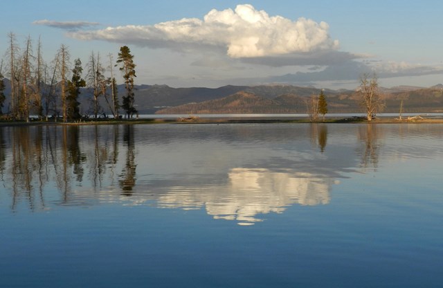 A cloud reflected into a large body of calm water 