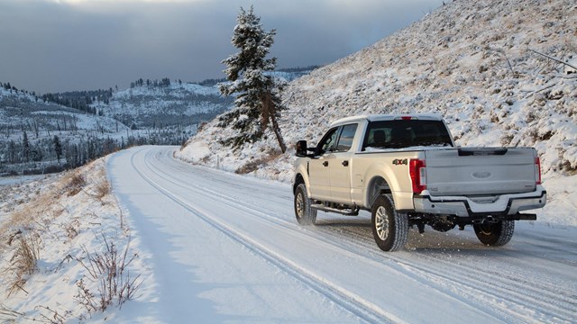A truck drives down a snow-covered road.