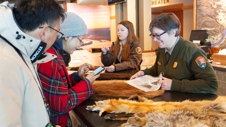 People in uniform at a desk helping visitors