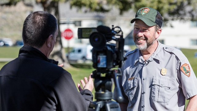 A park employee stands in front of a camera and answers questions.