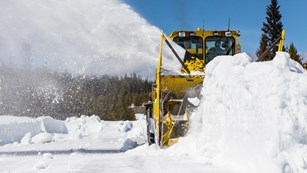 A vehicle cuts and blows snow on a road