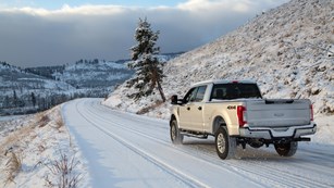 A truck drives along a snowy road.