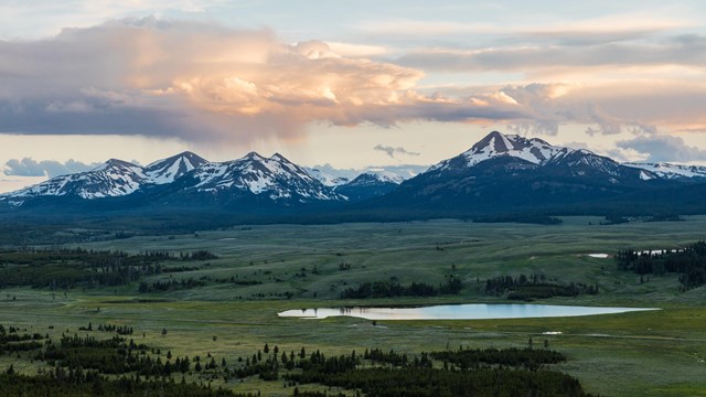 a wide view of a mountain range and small lake after a rainstorm