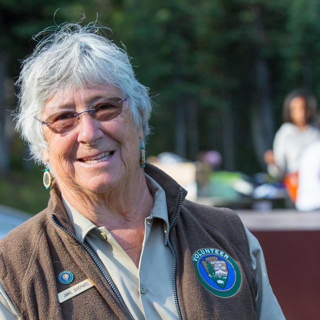 a woman with a volunteer patch on her vest is host at a park campground