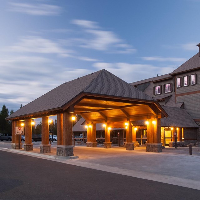 A large brown lodge is light under an evening sky.