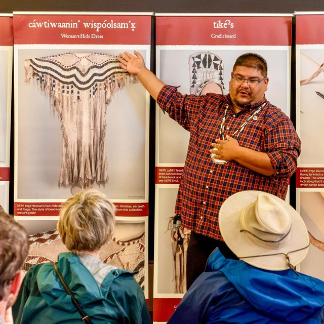 a man presenting and showing Indigenous artworks to a crowd of people