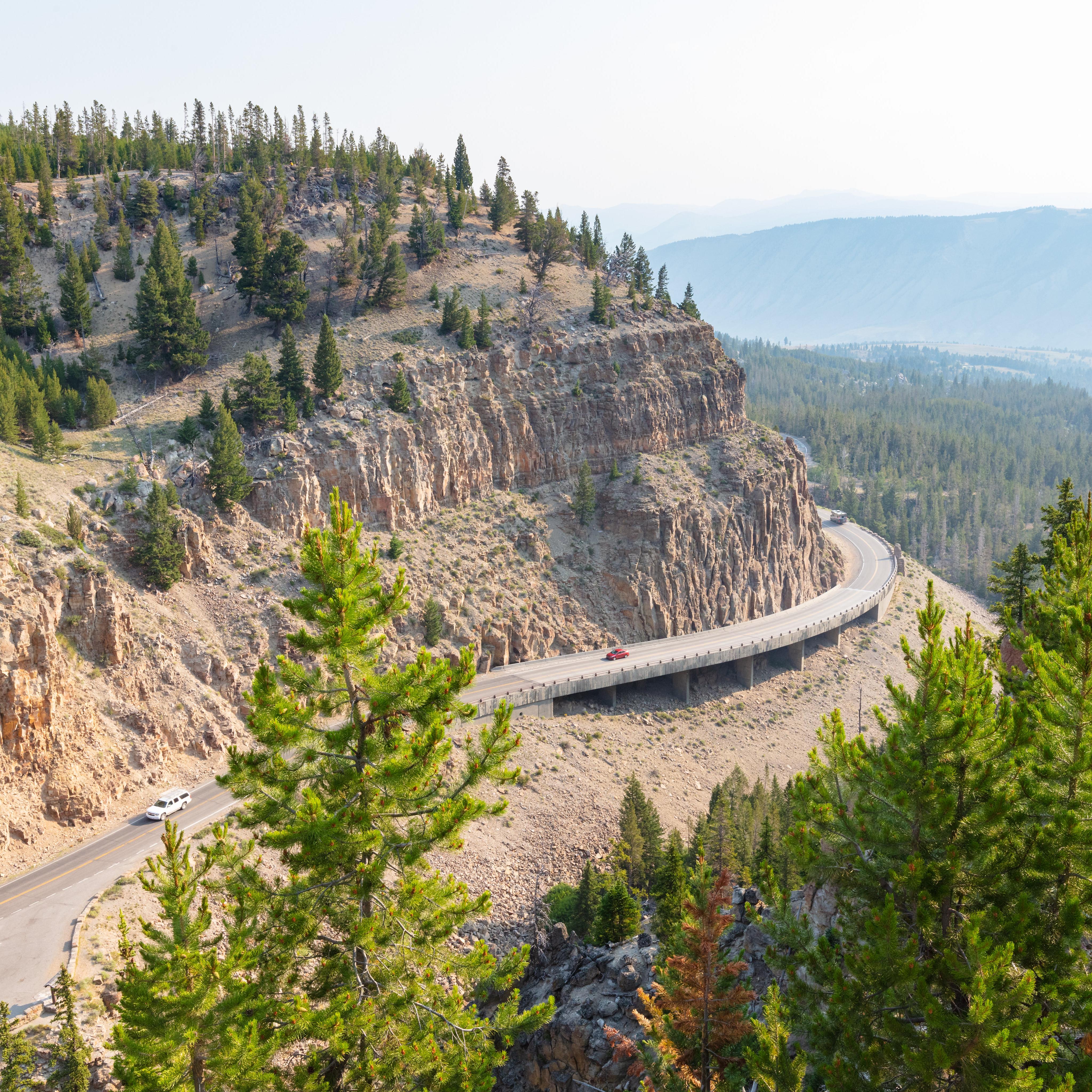 a windy road through mountains with smoky air conditions
