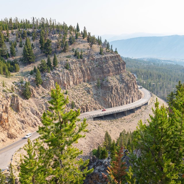a windy road through mountains with smoky air conditions