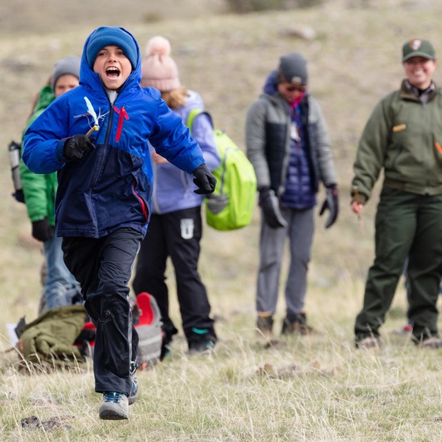 A students runs in front of classmates as part of an outdoor activity.
