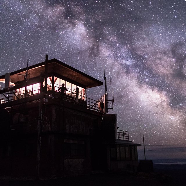 A fire tower with a galaxy in the sky. 