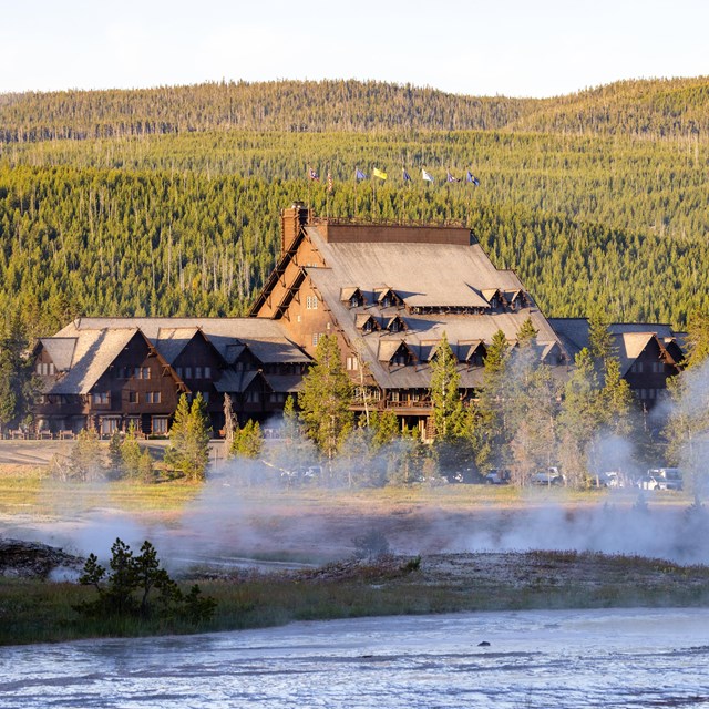steam rising in front of a large log structure at sunrise