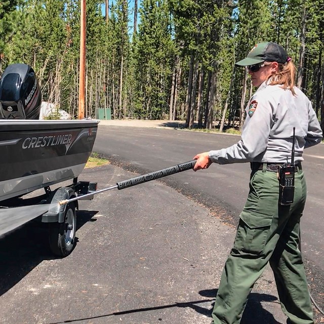 Photo of a park employee cleaning a boat with a power washer.