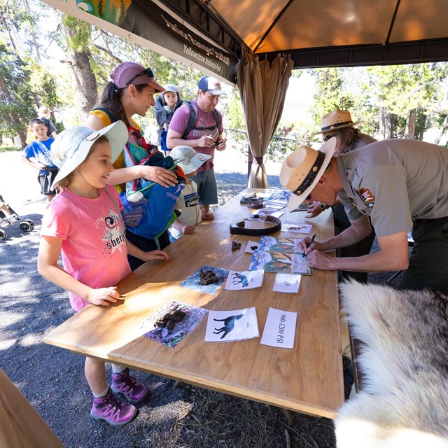 a family interacting with park rangers at an outdoor table