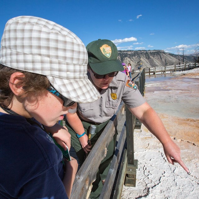 A ranger points out a hot spring to a young person