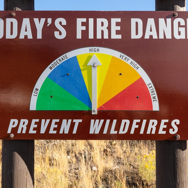 A large brown metal road sign with text: 