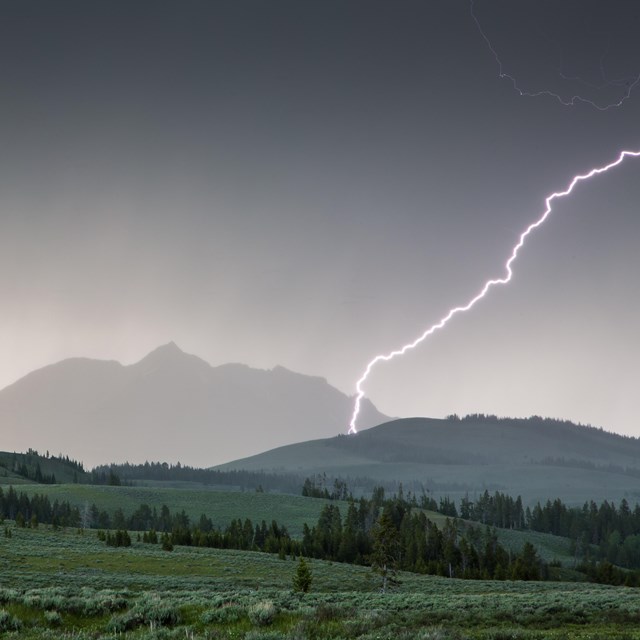 Lightning strikes Electric Peak as a dark storm rolls over the mountain.
