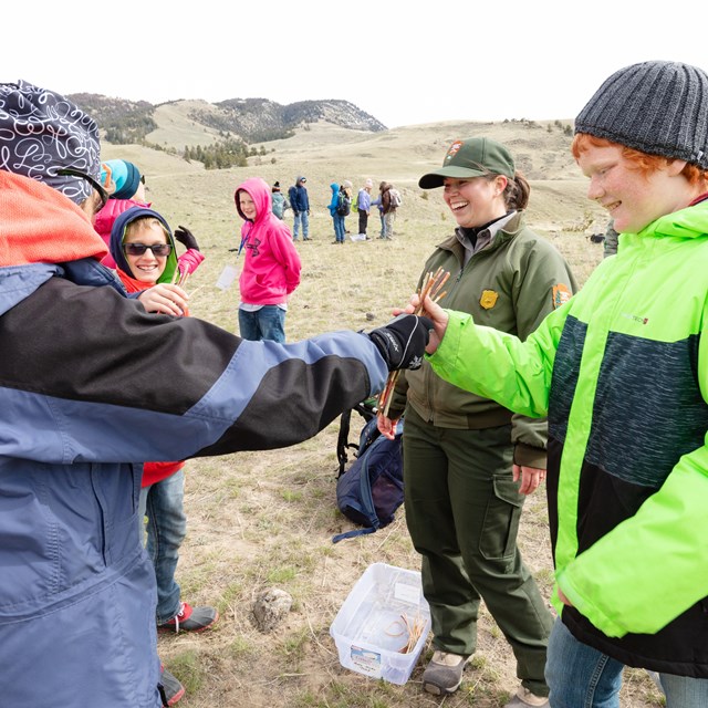 An employee and group of kids learning how to play a Chippewa game