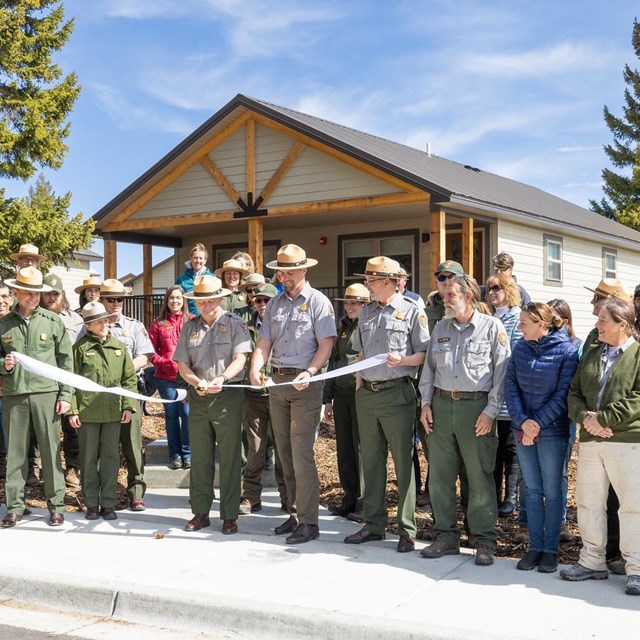 a group of park employees cutting a ribbon in front of brand-new employee housing