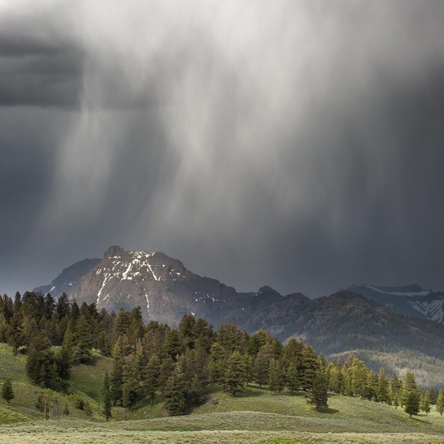 Rain clouds descend over jagged mountain peaks