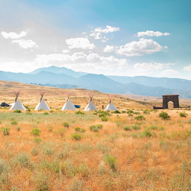 a line of teepees in front of mountains