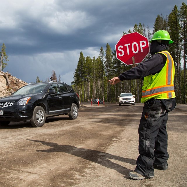 A flagger guides cars through road construction.