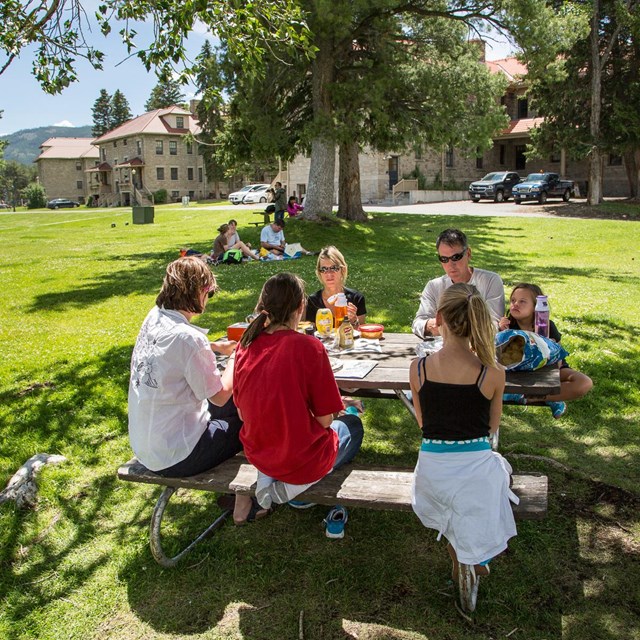 A family sits around a picnic table and enjoys a meal together.